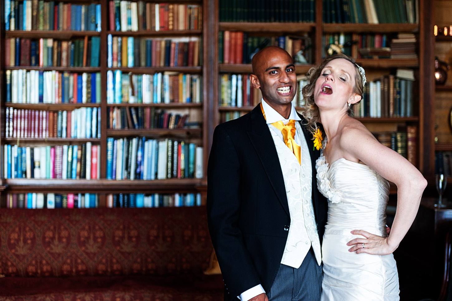 Bride and groom laughing in a wood-panelled library, UK wedding photography