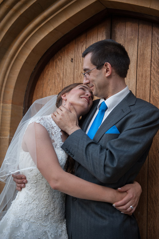 Bride and groom embracing in a wooden arched doorway, MadlyWed wedding photography